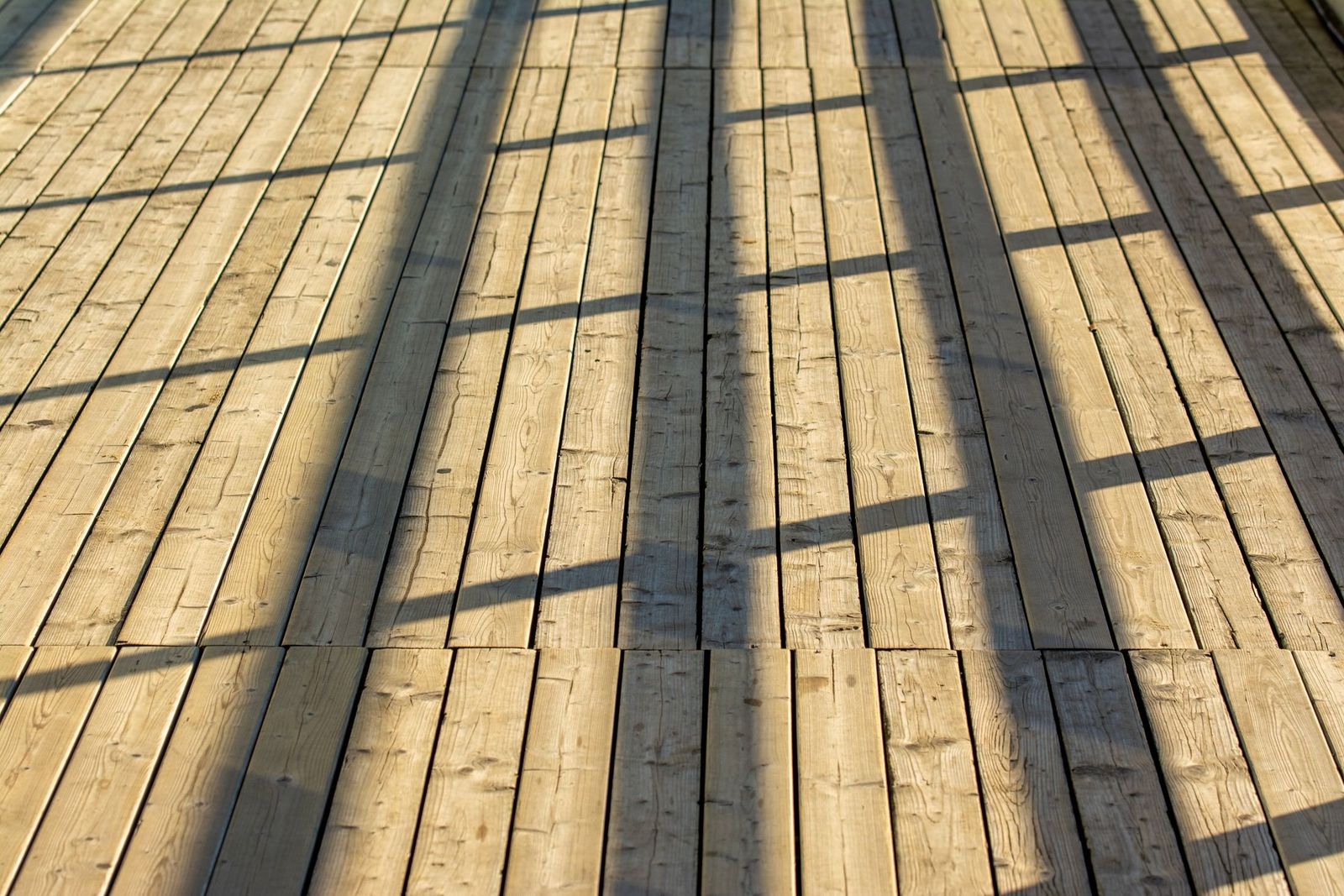 Holzterrasse im Sonnenlicht mit Geländerschatten